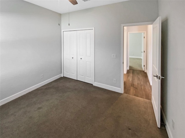 unfurnished bedroom with dark carpet, a closet, and ceiling fan