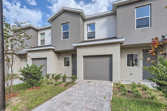 view of front facade with an attached garage, decorative driveway, and stucco siding