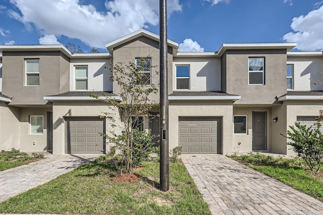 view of property with decorative driveway, an attached garage, and stucco siding