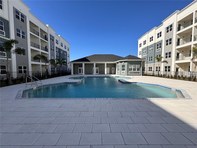 community pool featuring a jacuzzi, a patio area, and fence