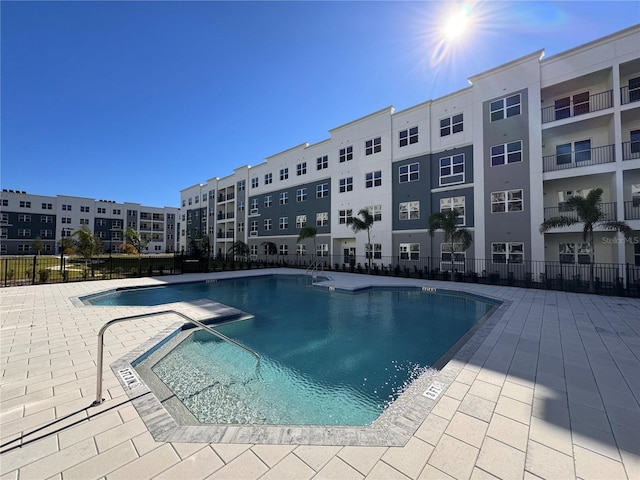 pool with a patio area and fence