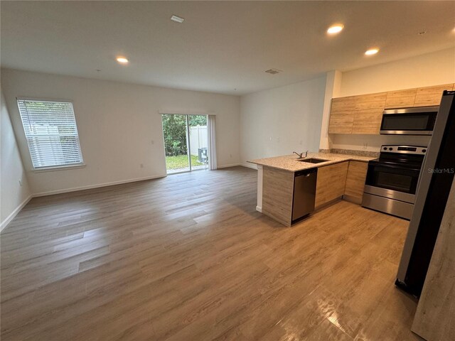 kitchen with modern cabinets, open floor plan, light countertops, a peninsula, and stainless steel appliances