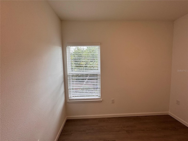 spare room with baseboards and dark wood finished floors
