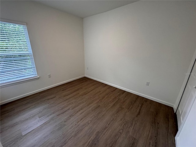 unfurnished room featuring baseboards, wood finished floors, and a healthy amount of sunlight