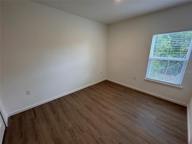 empty room with dark wood-type flooring and baseboards