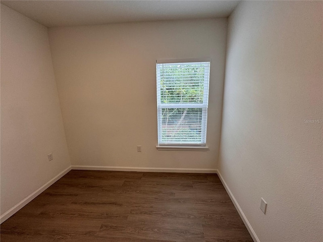 spare room with baseboards and dark wood finished floors