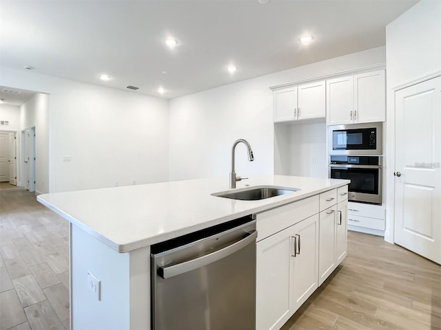 kitchen featuring sink, an island with sink, stainless steel appliances, light hardwood / wood-style floors, and white cabinets