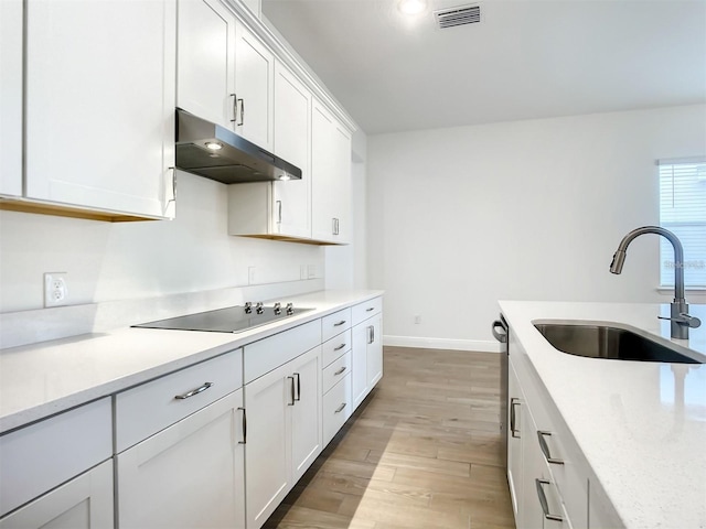 kitchen with sink, white cabinetry, light wood-type flooring, black electric stovetop, and light stone countertops