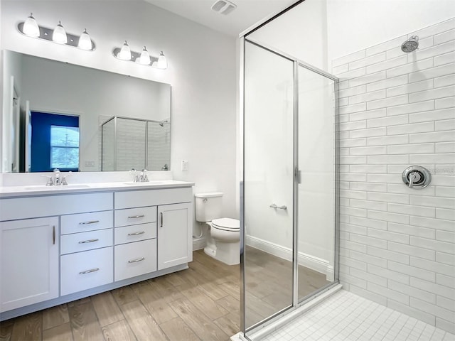 bathroom with hardwood / wood-style flooring, vanity, an enclosed shower, and toilet