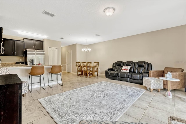 living room featuring light tile patterned floors, a chandelier, and a textured ceiling