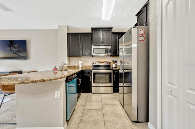 kitchen with sink, a breakfast bar area, light stone counters, kitchen peninsula, and stainless steel appliances