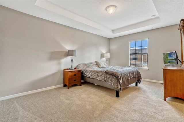 carpeted bedroom with a raised ceiling and a textured ceiling