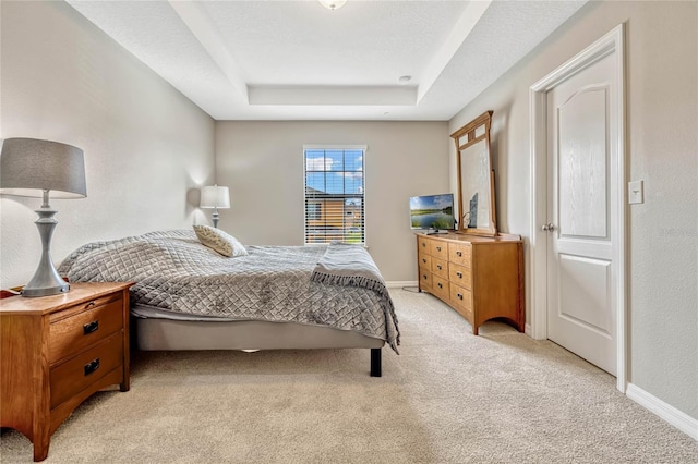 carpeted bedroom featuring a raised ceiling and a textured ceiling