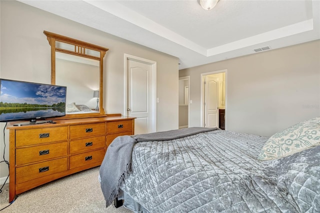 bedroom with a raised ceiling and light carpet