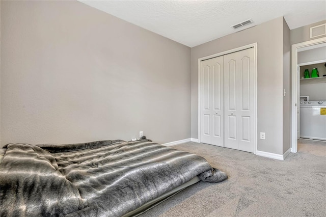 carpeted bedroom with washer / clothes dryer, a textured ceiling, and a closet