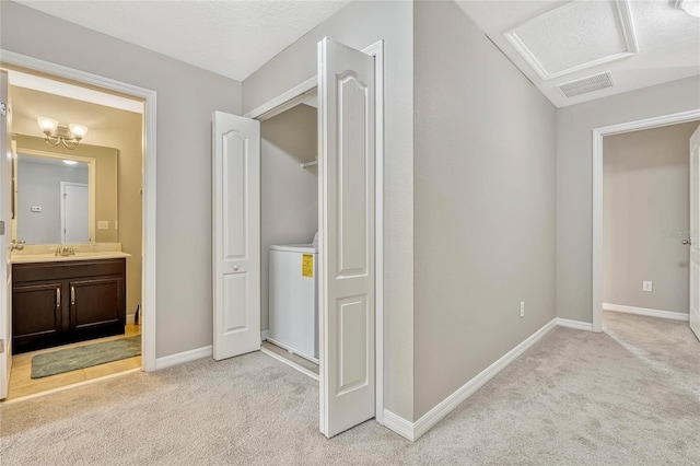 hallway with sink, light carpet, and a textured ceiling