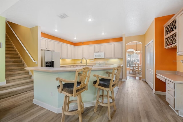 126 Seville Chase Dr, Winter Springs, FL 32708 - kitchen with white appliances, wood finished floors, light countertops, a kitchen bar, and recessed lighting