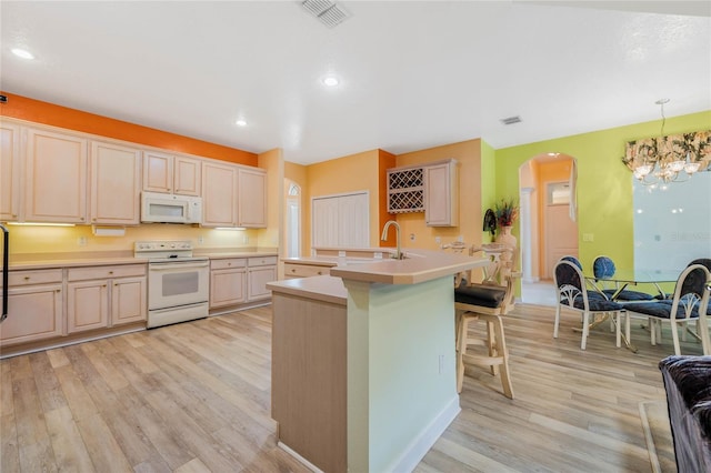 126 Seville Chase Dr, Winter Springs, FL 32708 - kitchen featuring white appliances, arched walkways, light wood finished floors, a center island with sink, and recessed lighting