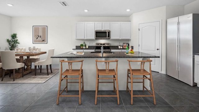 kitchen featuring white cabinetry, appliances with stainless steel finishes, and an island with sink