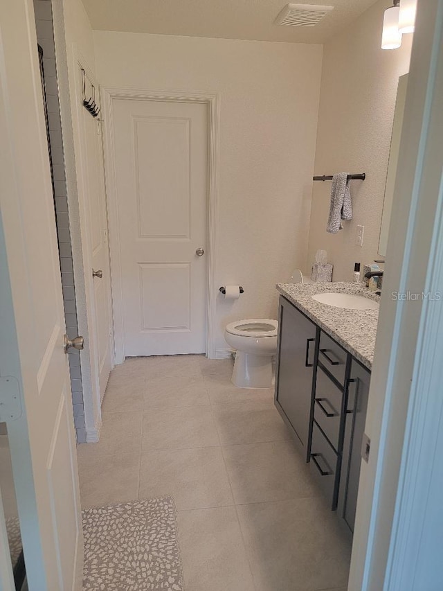 bathroom featuring vanity, tile patterned flooring, and toilet