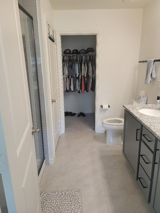 bathroom featuring vanity, toilet, a shower with shower door, and tile patterned flooring