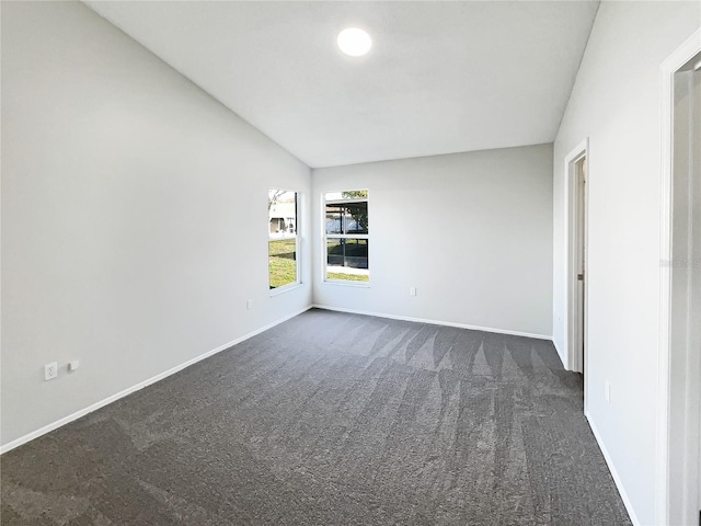 carpeted spare room with vaulted ceiling