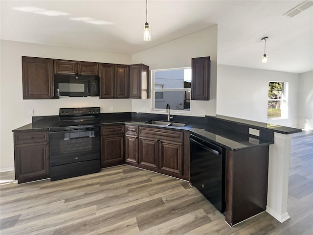 kitchen featuring sink, decorative light fixtures, kitchen peninsula, light hardwood / wood-style floors, and black appliances