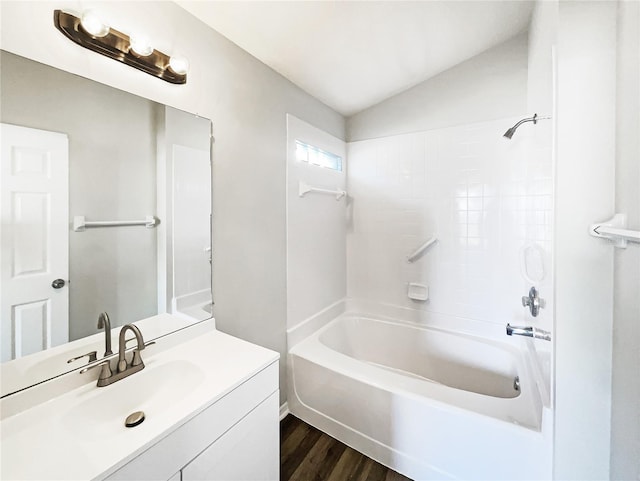 bathroom with vaulted ceiling, hardwood / wood-style floors, vanity, and shower / bathtub combination