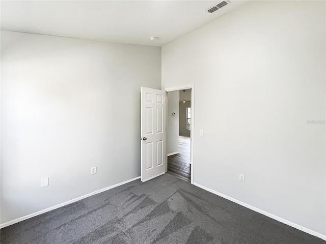 spare room featuring dark carpet and vaulted ceiling