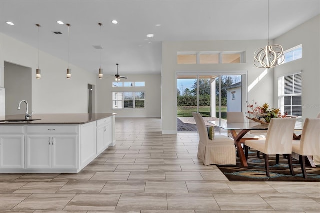 dining room featuring ceiling fan with notable chandelier, sink, a high ceiling, and a wealth of natural light