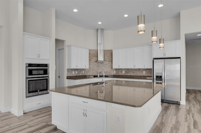 kitchen with a kitchen island with sink, white cabinetry, and appliances with stainless steel finishes