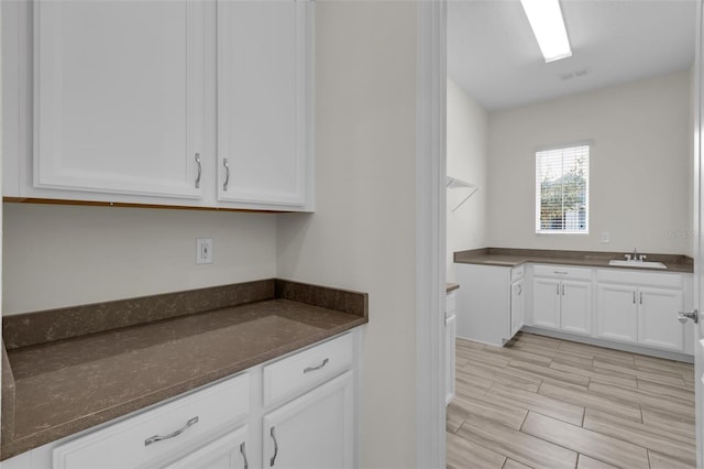 kitchen with white cabinetry, sink, and dark stone countertops