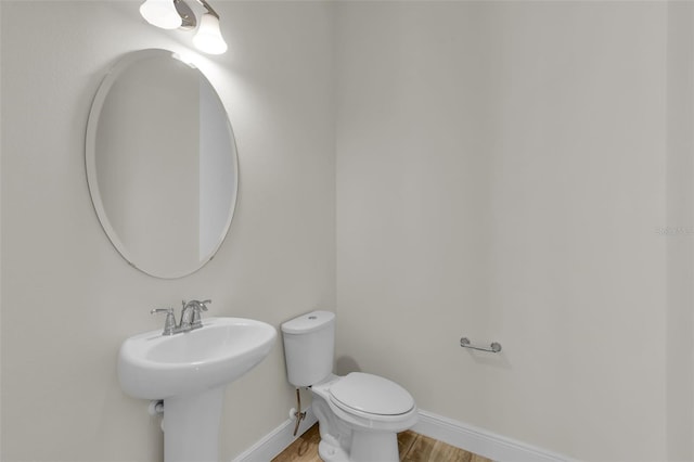 bathroom with wood-type flooring, toilet, and sink