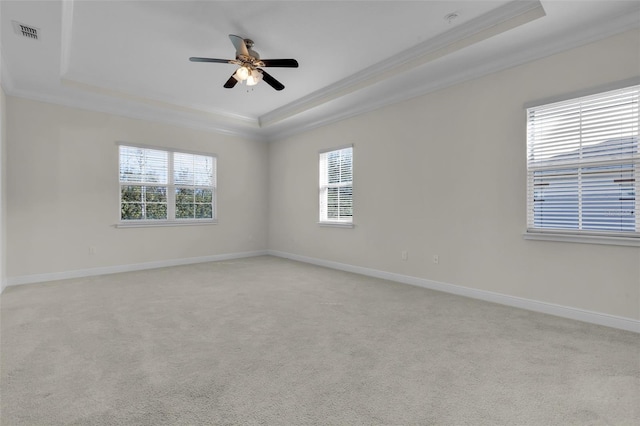 empty room featuring light carpet, ornamental molding, and a raised ceiling