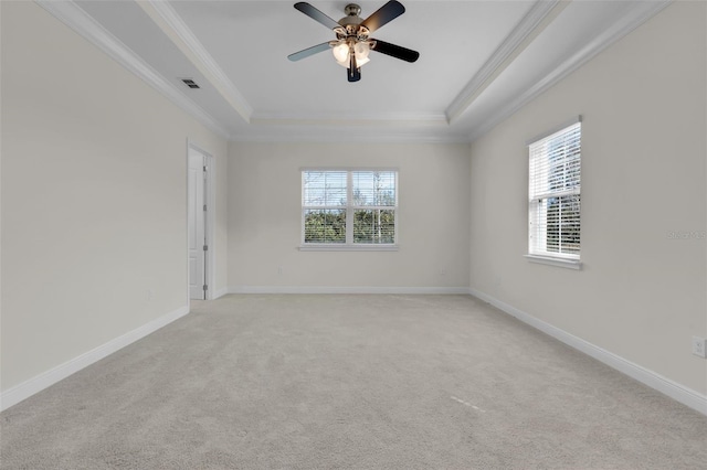 carpeted spare room with ornamental molding, a raised ceiling, and a wealth of natural light