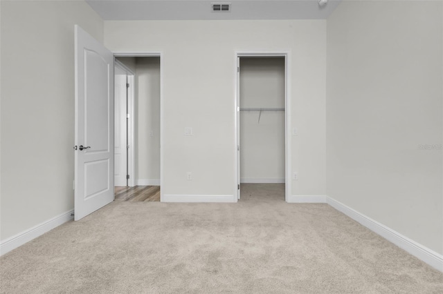 unfurnished bedroom with light carpet, a walk in closet, and a closet