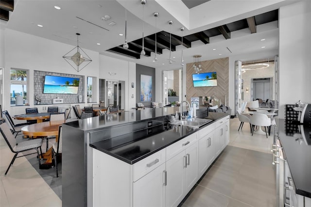 kitchen with a spacious island, sink, white cabinetry, hanging light fixtures, and beam ceiling