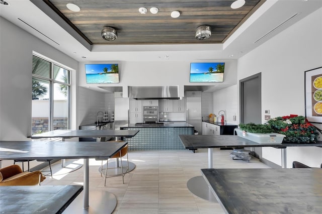 tiled dining area featuring wood ceiling, a tray ceiling, and a high ceiling