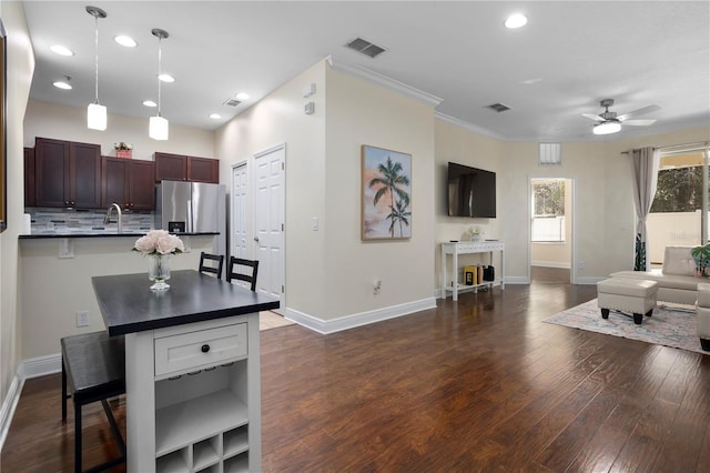 kitchen with dark hardwood / wood-style floors, a breakfast bar area, decorative backsplash, hanging light fixtures, and stainless steel fridge with ice dispenser