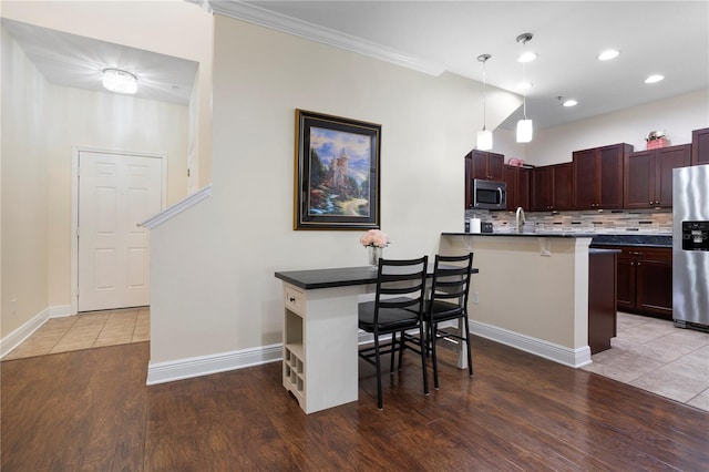 kitchen featuring appliances with stainless steel finishes, kitchen peninsula, hanging light fixtures, and a breakfast bar area