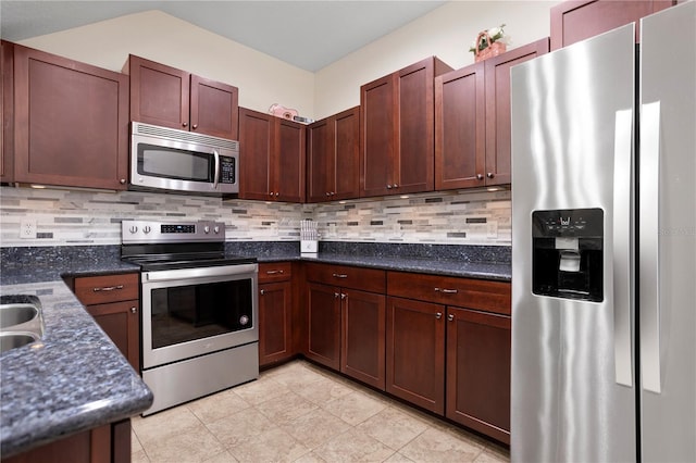 kitchen with appliances with stainless steel finishes, light tile patterned floors, backsplash, and dark stone counters