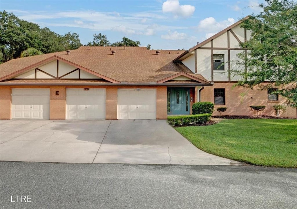 tudor home with a garage and a front yard