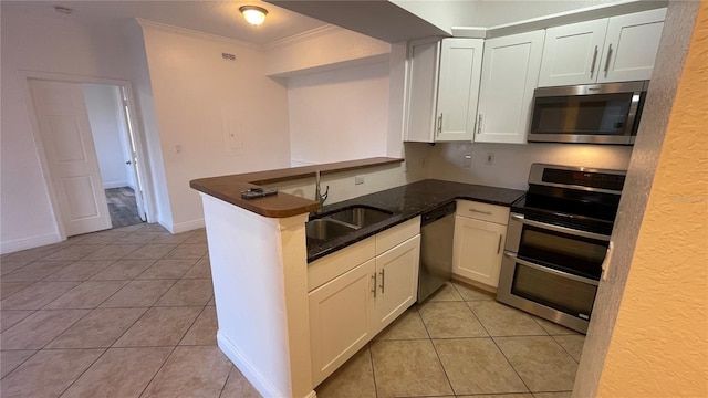 kitchen featuring light tile patterned flooring, appliances with stainless steel finishes, kitchen peninsula, and white cabinets