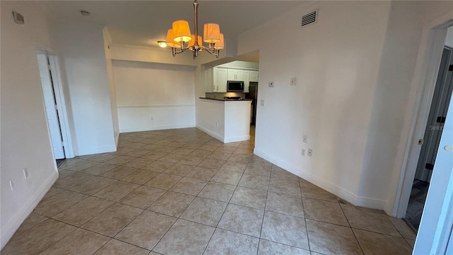 unfurnished room with a notable chandelier and light tile patterned floors