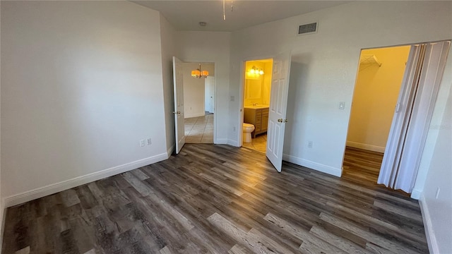 unfurnished bedroom featuring a walk in closet, connected bathroom, and dark hardwood / wood-style flooring