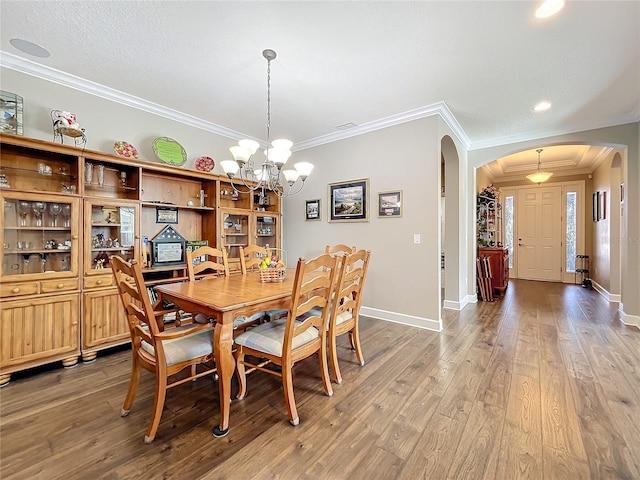 dining area with ornamental molding, hardwood / wood-style floors, and an inviting chandelier