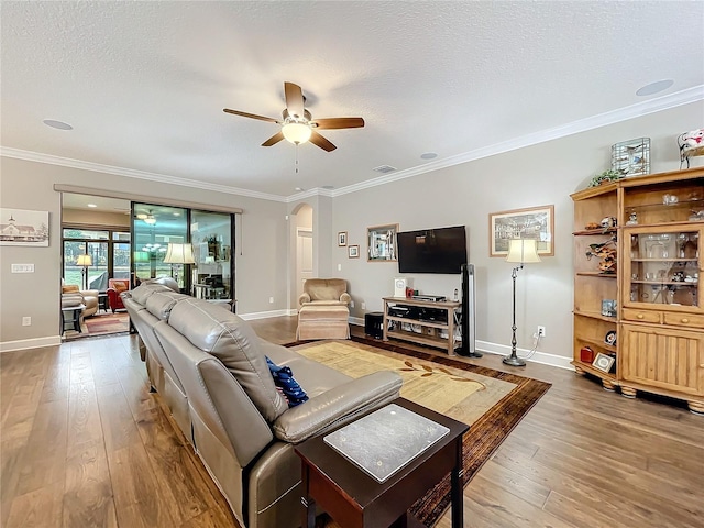 living room with ceiling fan, crown molding, wood-type flooring, and a textured ceiling