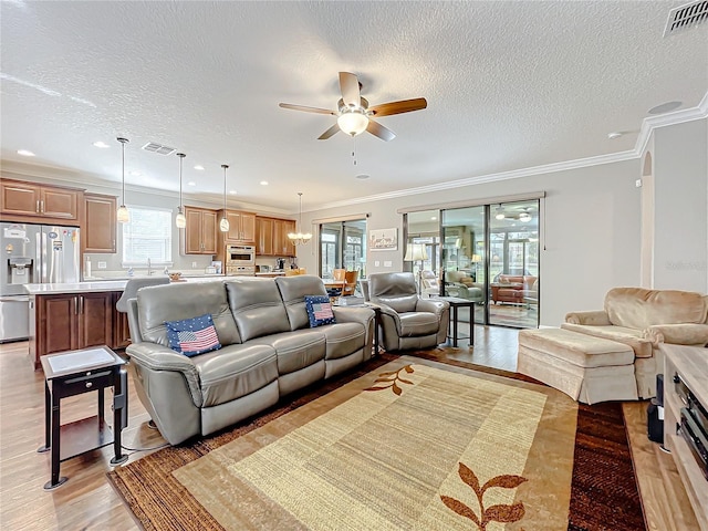 living room with crown molding, ceiling fan, light hardwood / wood-style floors, and a textured ceiling