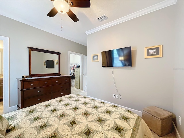 carpeted bedroom featuring a walk in closet, ornamental molding, a closet, and ceiling fan