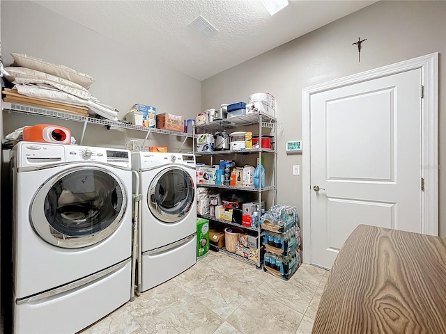 clothes washing area with washing machine and clothes dryer and a textured ceiling